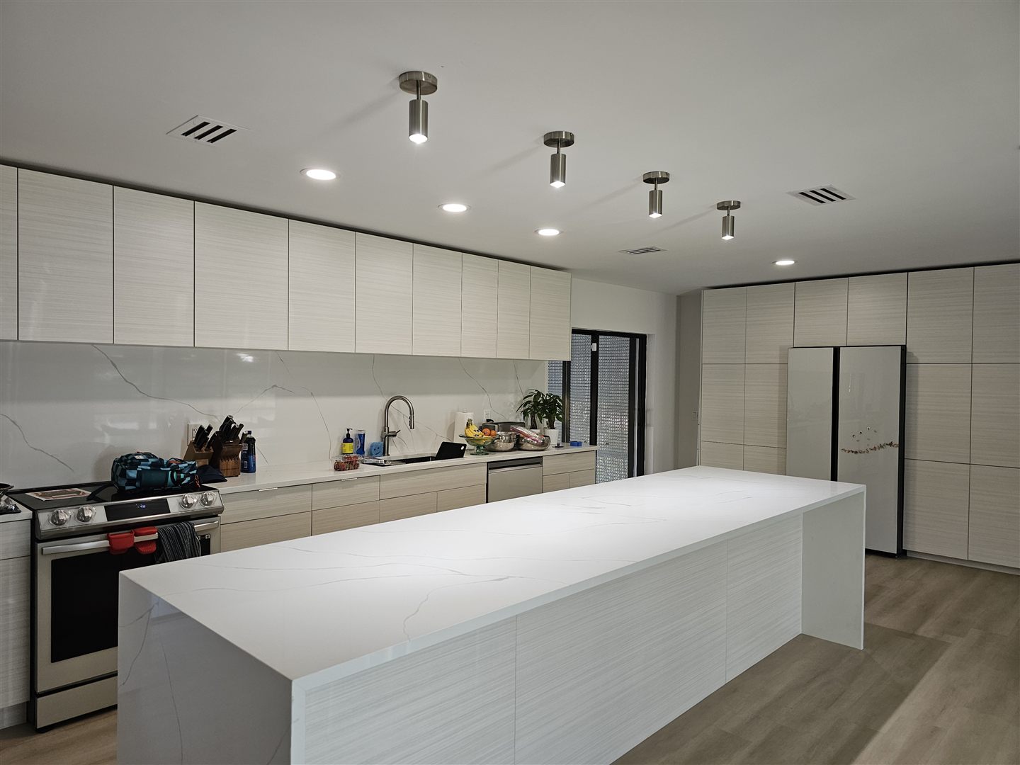 Pendant and recessed lighting in a bright white kitchen