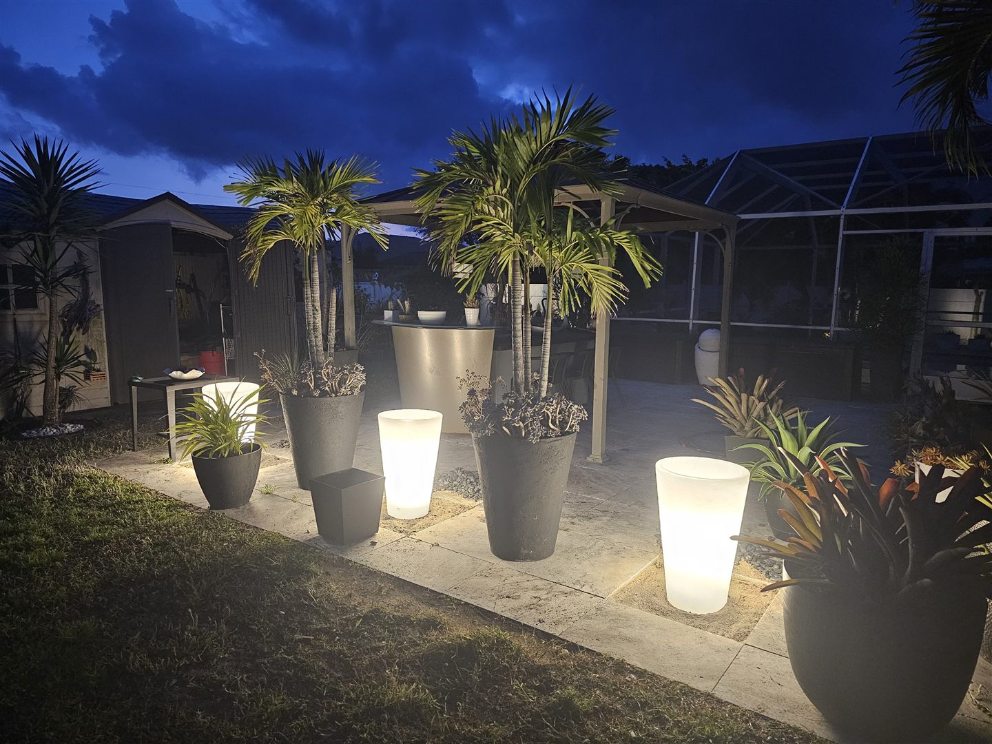Outdoor planters and palm trees illuminated beside a patio
